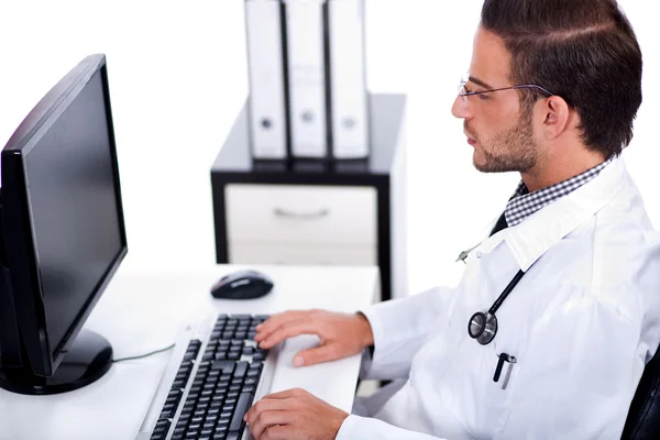 Αρσενικό ιατρός που εργάζεται με το desktop στο γραφείο του — Φωτογραφία Αρχείου