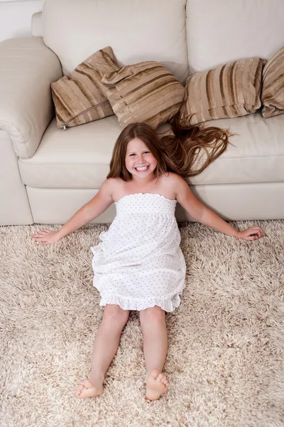 Menina bonita sentada no tapete — Fotografia de Stock
