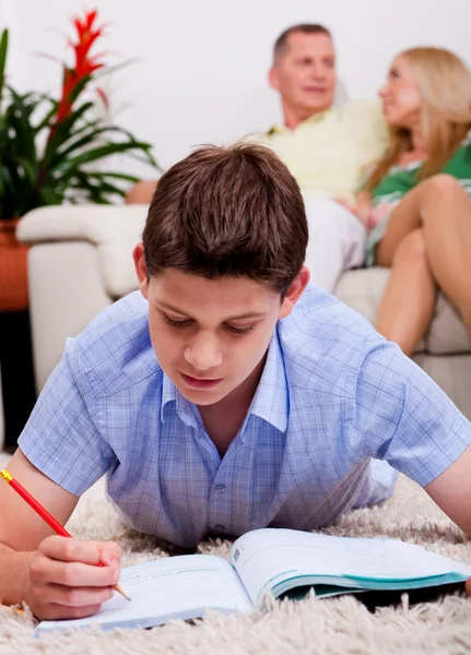 Ung pojke studera med familj i bakgrunden — Stockfoto