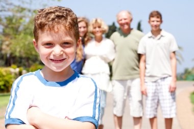 Young cute boy in focus with family in the background clipart
