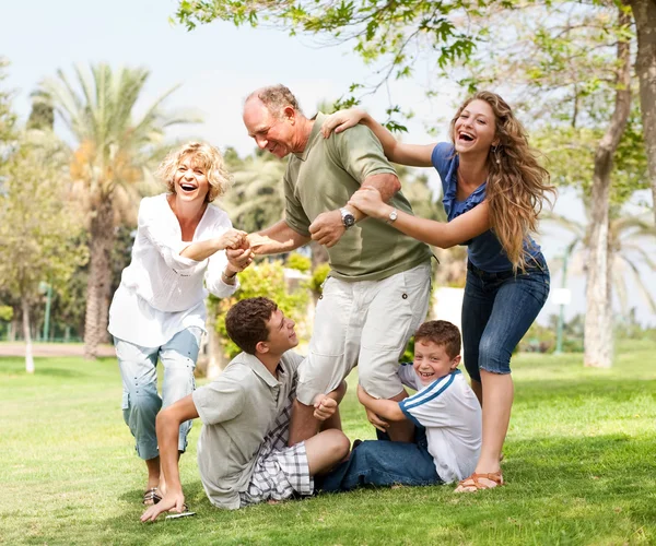 Family holding back grandfather and having fun — Stock Photo, Image