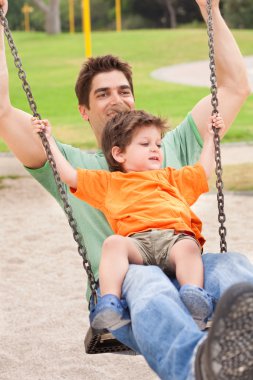 Father enjoying swing ride with his son clipart