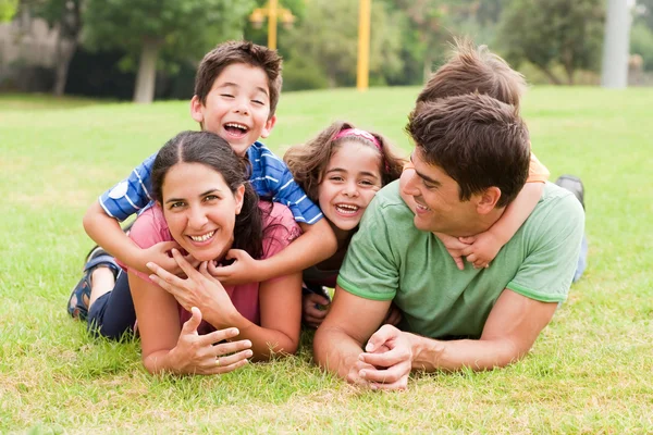 Игривая семья лежит на открытом воздухе и улыбается — стоковое фото