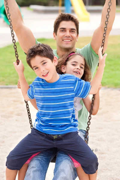 Pai e crianças desfrutando de passeio de balanço — Fotografia de Stock