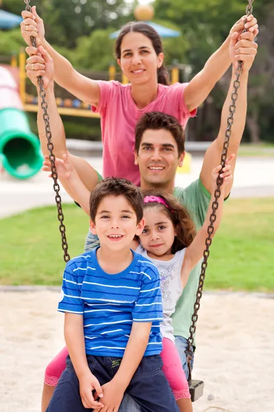 Família caucasiana alegre balançando no parque — Fotografia de Stock