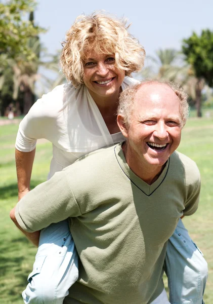 Senior man giving piggy ride to her wife — Stock Photo, Image