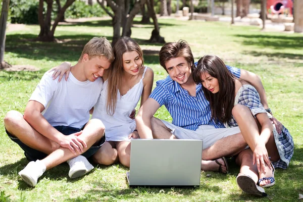 Vrienden genieten van film in park op laptop — Stockfoto