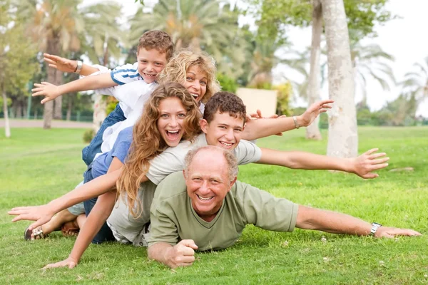 Família feliz colocando um no outro — Fotografia de Stock