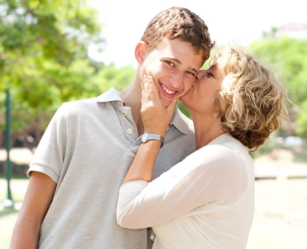 Porträt einer glücklichen Seniorin, die ihren Enkel küsst — Stockfoto