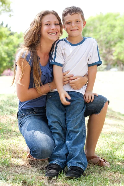 Bild einer fürsorglichen Mutter, die ihren Sohn im Park umarmt — Stockfoto