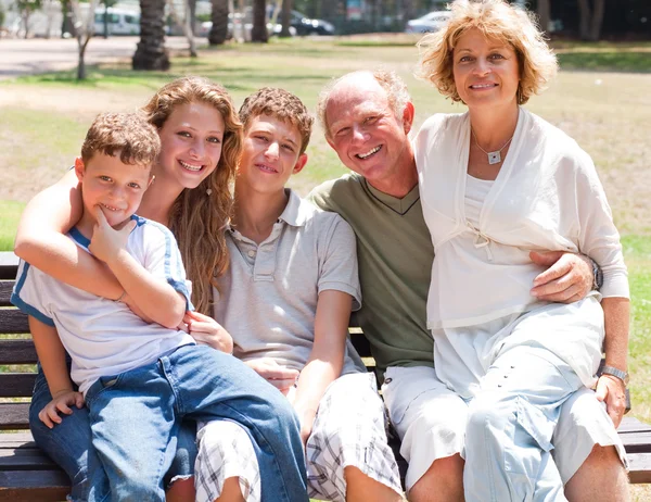 Boldog család ül a padon — Stock Fotó