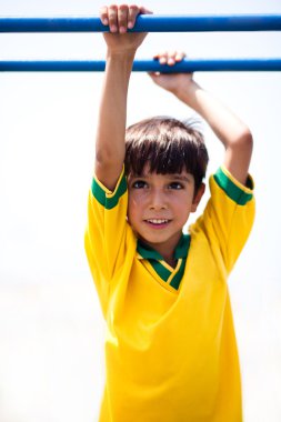 Young boy hanging on jungle gym clipart