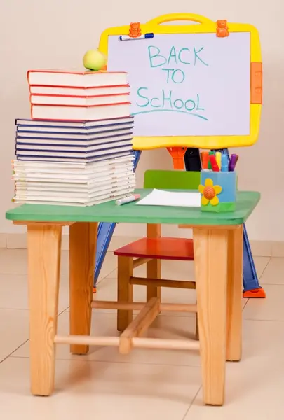 Школьные книги и яблоко на столе с эскизами — стоковое фото