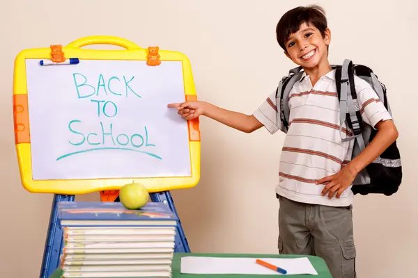 微笑的学校男孩指着白板 免版税图库图片