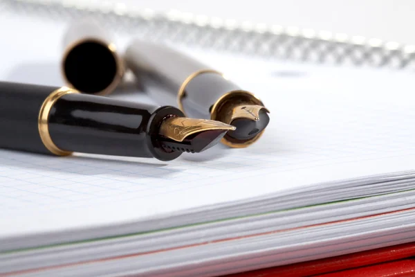Fountain pens lays on a writing-book — Stock Photo, Image