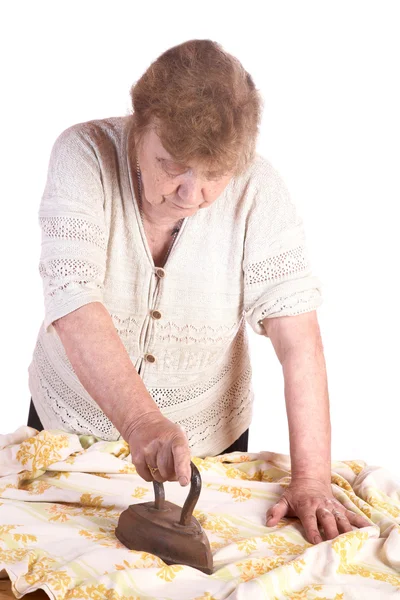 Стара жінка прасує тканину — стокове фото