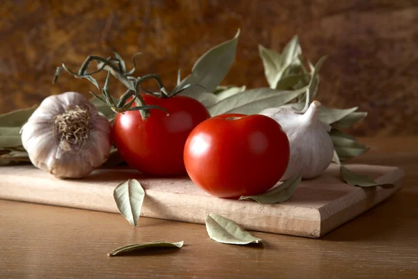 Tomaten knoflook en laurierblad takken op tafel — Stockfoto