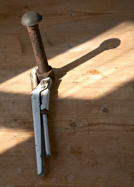 Регулируемый гаечный ключ и ржавый болт с гайкой на столе — стоковое фото