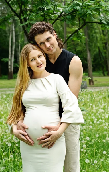Красивая беременная женщина с мужем в парке — стоковое фото