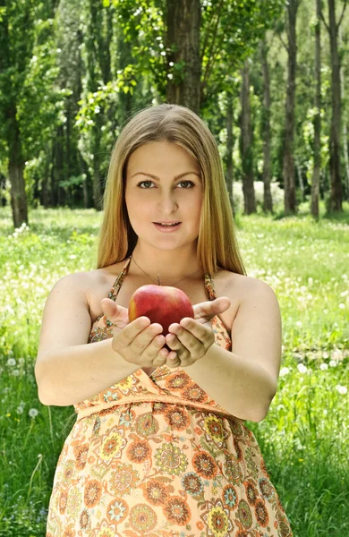 Pregnant woman with apple in the park — Stock Photo, Image