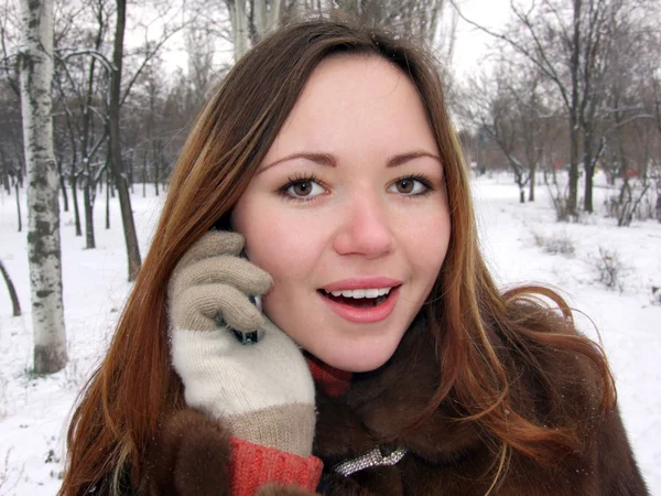 Het meisje in de winter in park spreekt door — Stockfoto