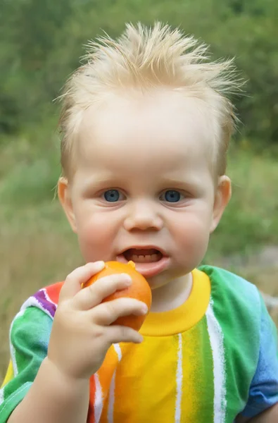O rapaz encantador com tangerina — Fotografia de Stock