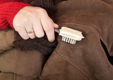 Cleaning a sheepskin with whisk broom clipart