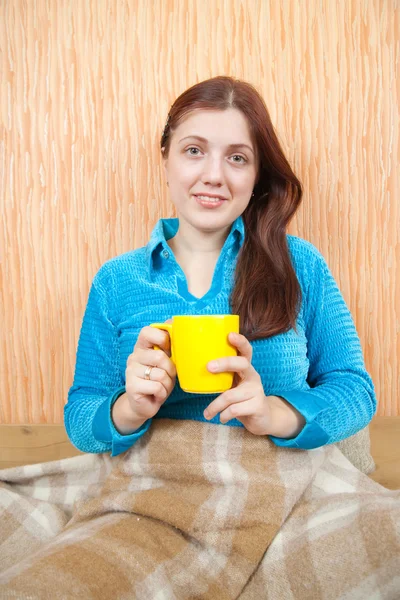 Девушка расслабляется с желтой чашкой дома — стоковое фото
