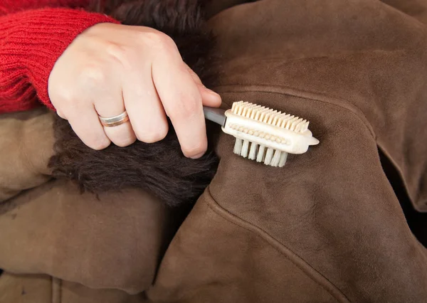 Cleaning a sheepskin with whisk broom — Stock Photo, Image