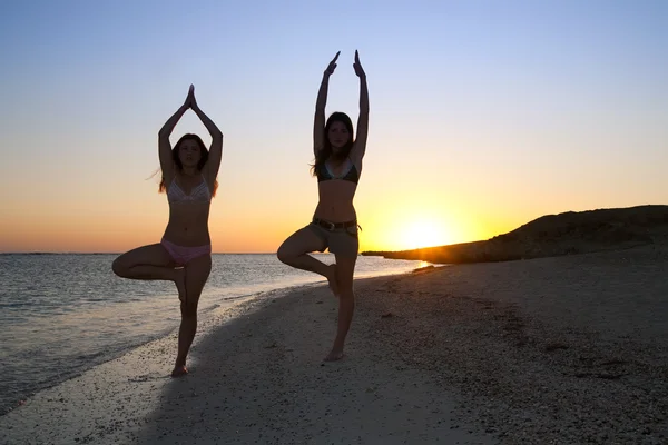 Les filles font du yoga contre le coucher du soleil — Photo