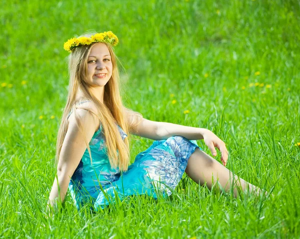 Girl in chaplet is sitting in meadow — Stock Photo, Image