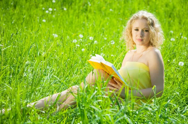 Girl reading book in grass — Stock Photo, Image