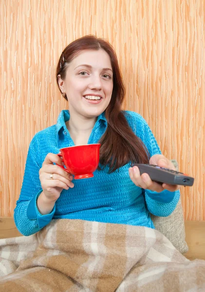 Kvinnan ler med TV-fjärrkontrollen — Stockfoto