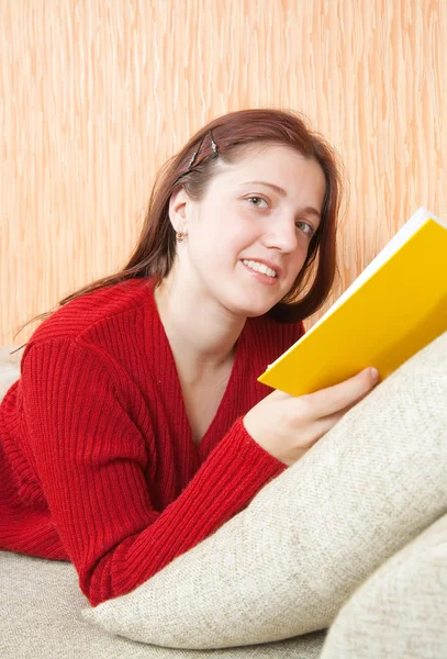 Красива молода дівчина читає книгу на дивані — стокове фото
