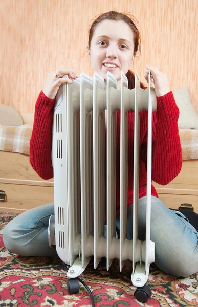 Girl is sitting by a oil heater — Stock Photo, Image