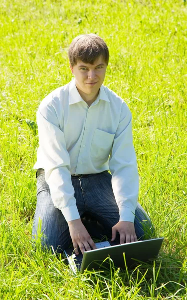 Uomo che lavora sul computer portatile in prato — Foto Stock
