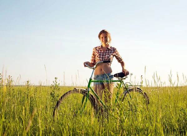 Girl with bicycle in grass — Stock Photo, Image