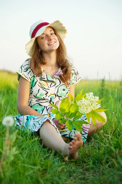 Girl in hat is sitting on meadow — Stock Photo, Image
