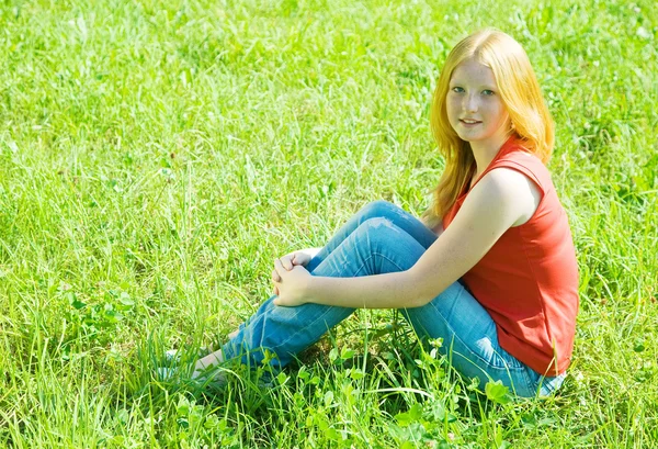 Tiener meisje zit in gras — Stockfoto