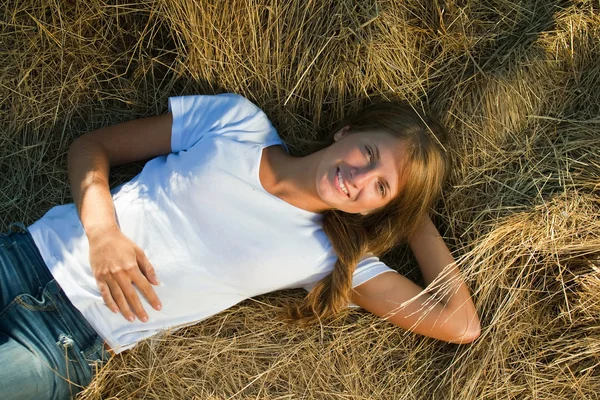 Menina descansando sobre palha fresca — Fotografia de Stock