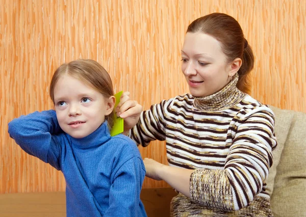 Mère peigne les cheveux de sa fille — Photo