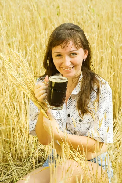 Девушка с пивом на зерновом поле — стоковое фото