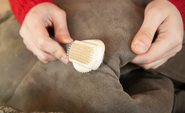 Mujer limpiando una piel de oveja con escoba batidora —  Fotos de Stock
