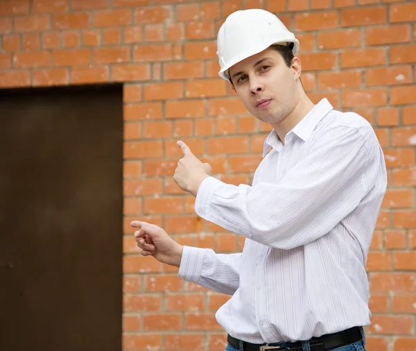 Constructor señalando a la puerta en la pared de ladrillo —  Fotos de Stock