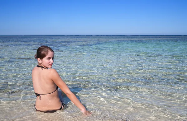 Meisje, zittend op de koraal kust — Stockfoto
