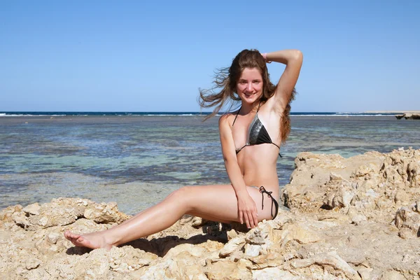 Chica de pelo largo tomando el sol sobre piedras —  Fotos de Stock