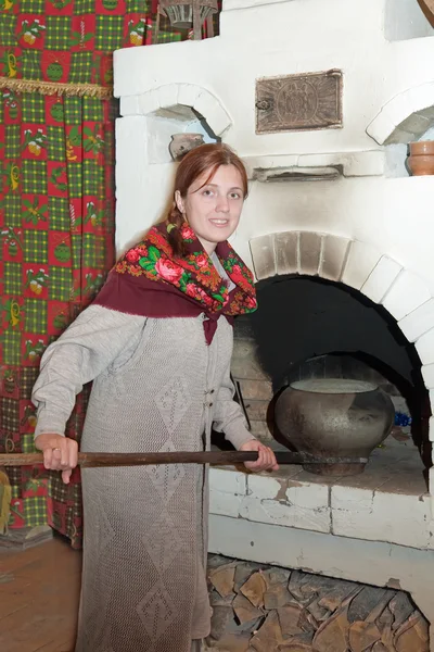 Mulher coloca uma panela no fogão russo — Fotografia de Stock