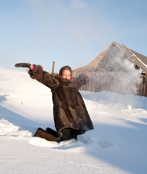 Girl in fur coat throwing snowflakes — Stockfoto