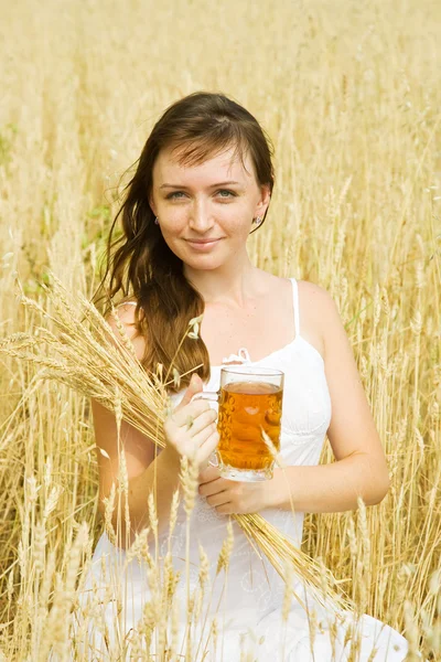 Дівчина з пивом на полі зернових — стокове фото