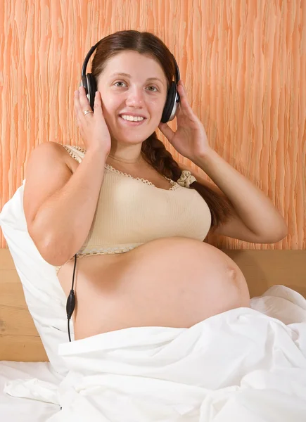 Terhes nő, zenehallgatás — Stock Fotó